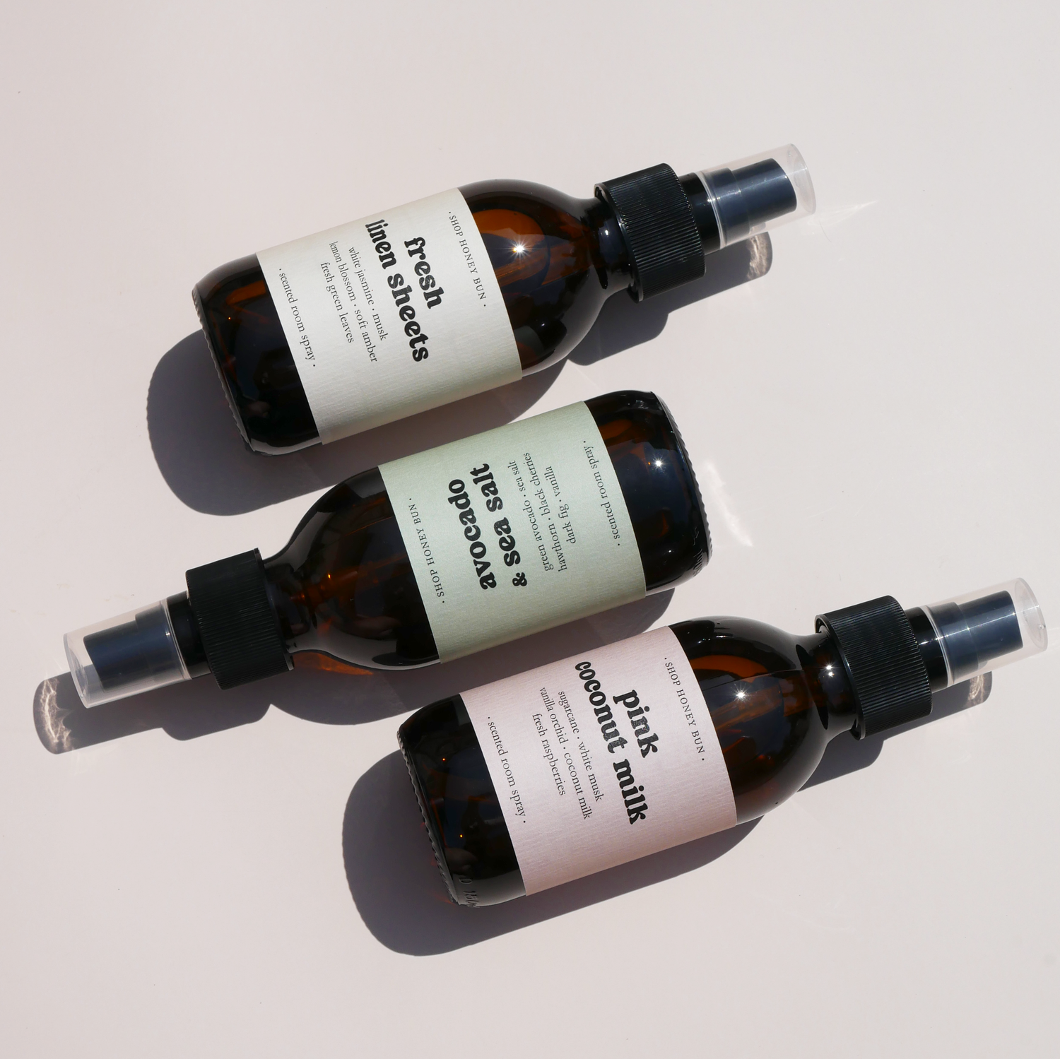 Three scented room sprays in amber glass jars with pastel coloured labels