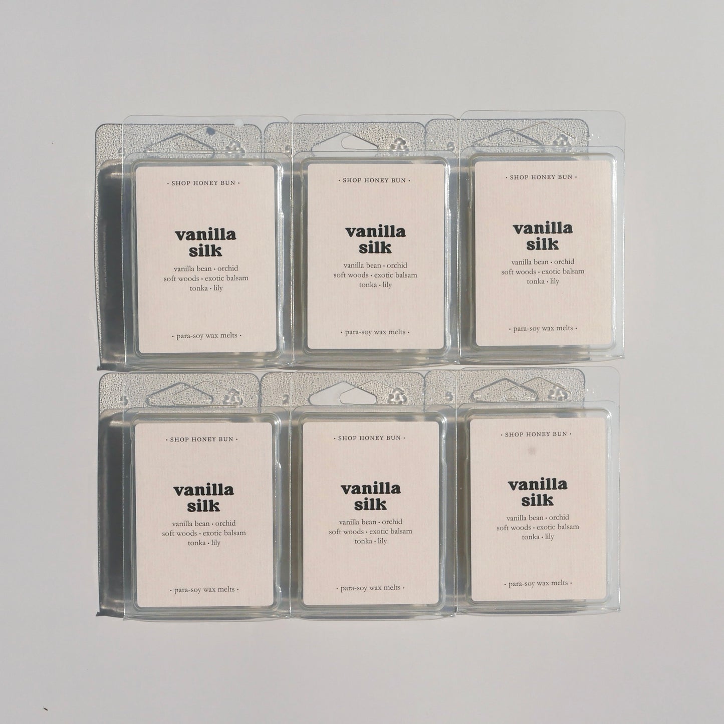 Six vanilla silk scented clamshells on a beige background
