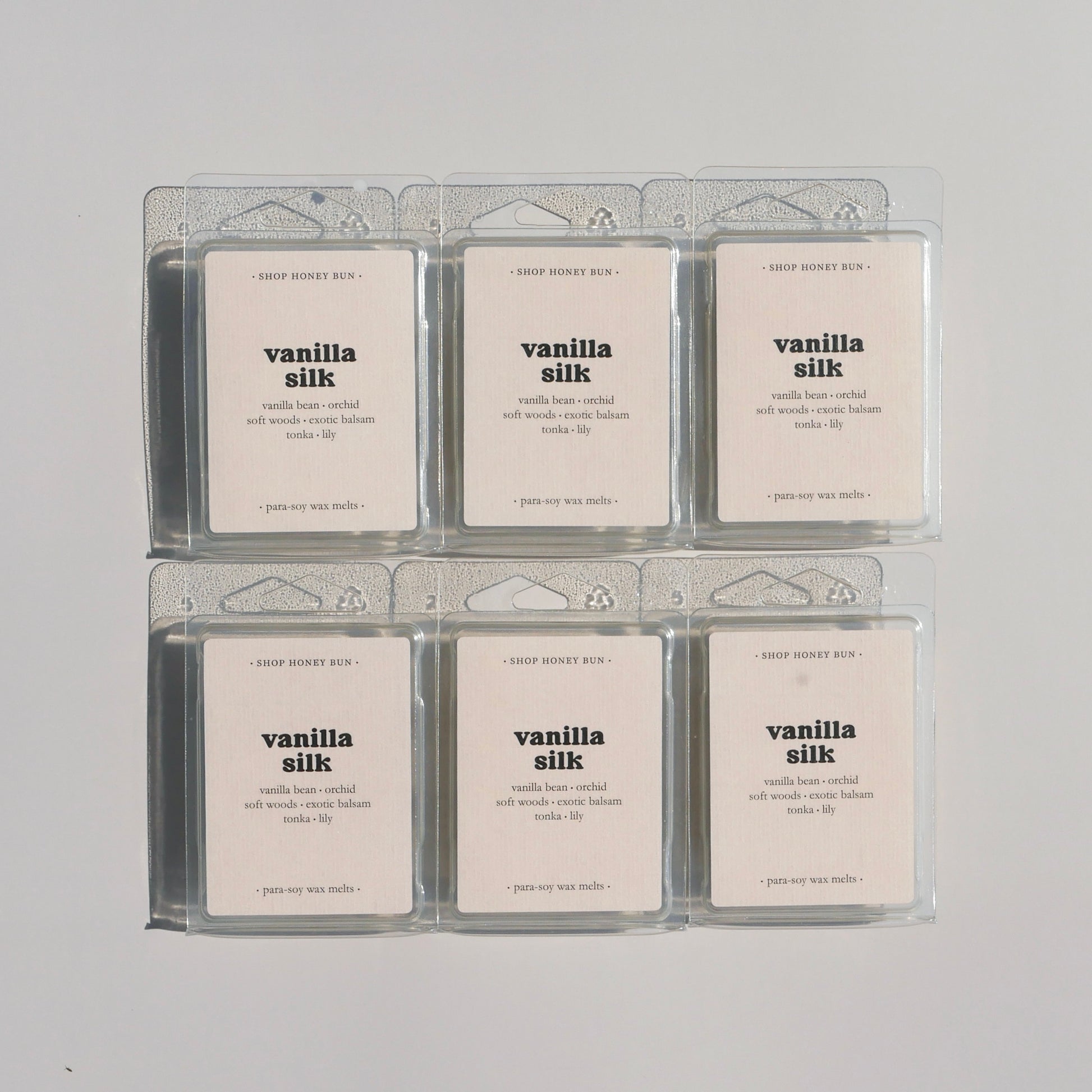 Six vanilla silk scented clamshells on a beige background
