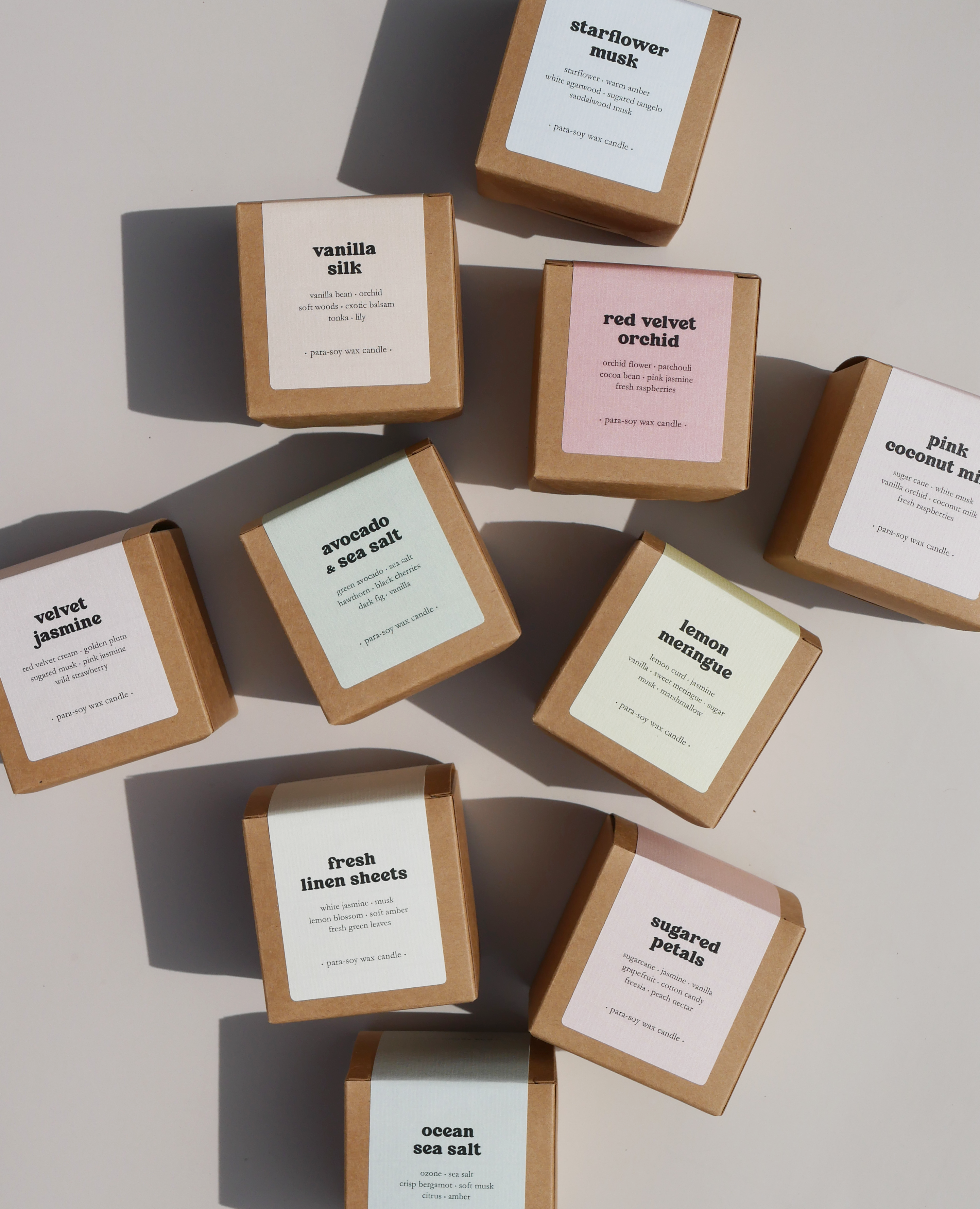 Ten scented candles n brown kraft boxes with pastel paper labels on a beige background