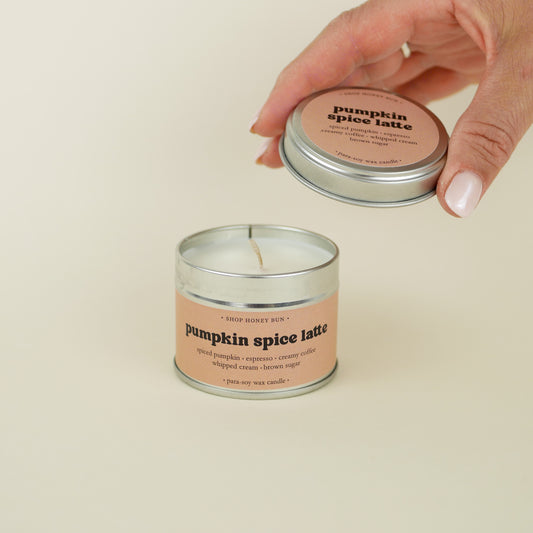 A 20 hour burn time pumpkin spice latte scented in candle with a hand lifting off the lid to show the candle wick
