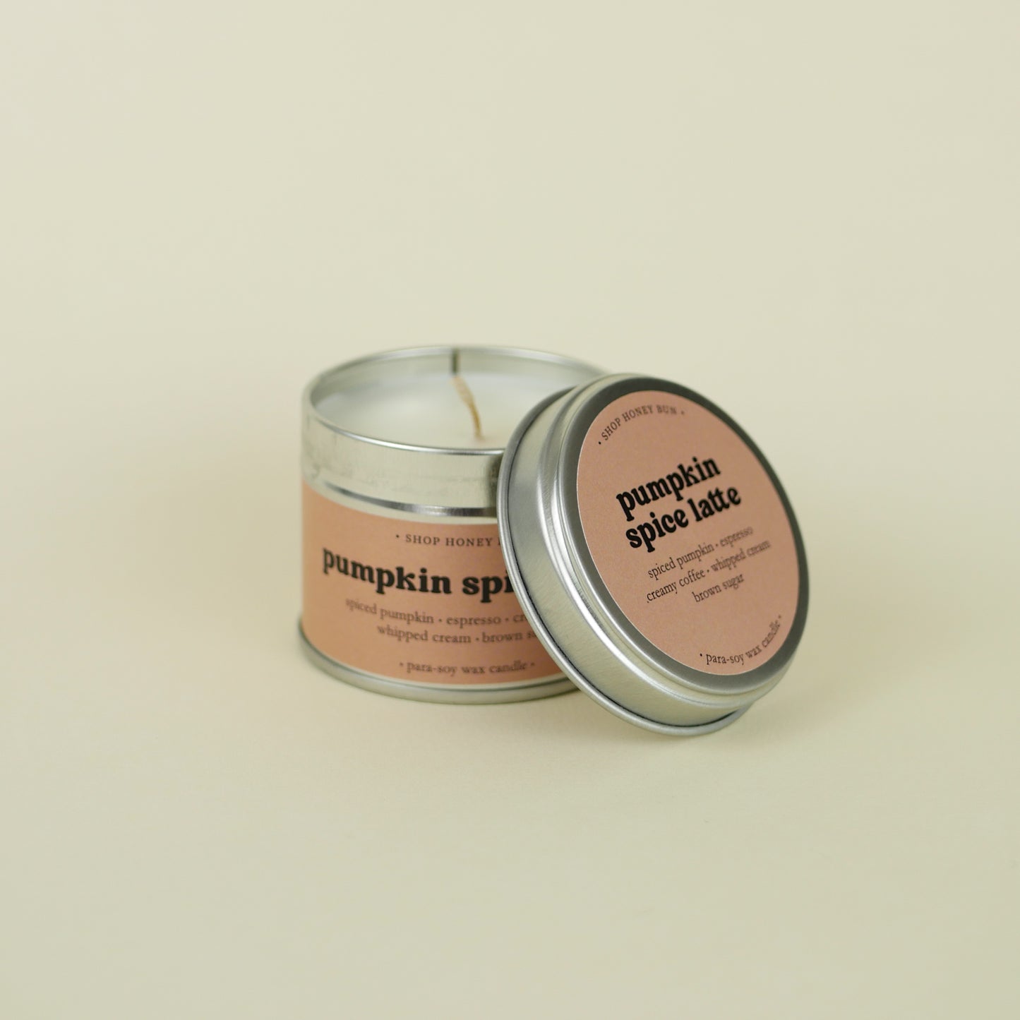 A 20 hour burn time pumpkin spice latte scented in candle with a hand lifting off the lid to show the candle wick
