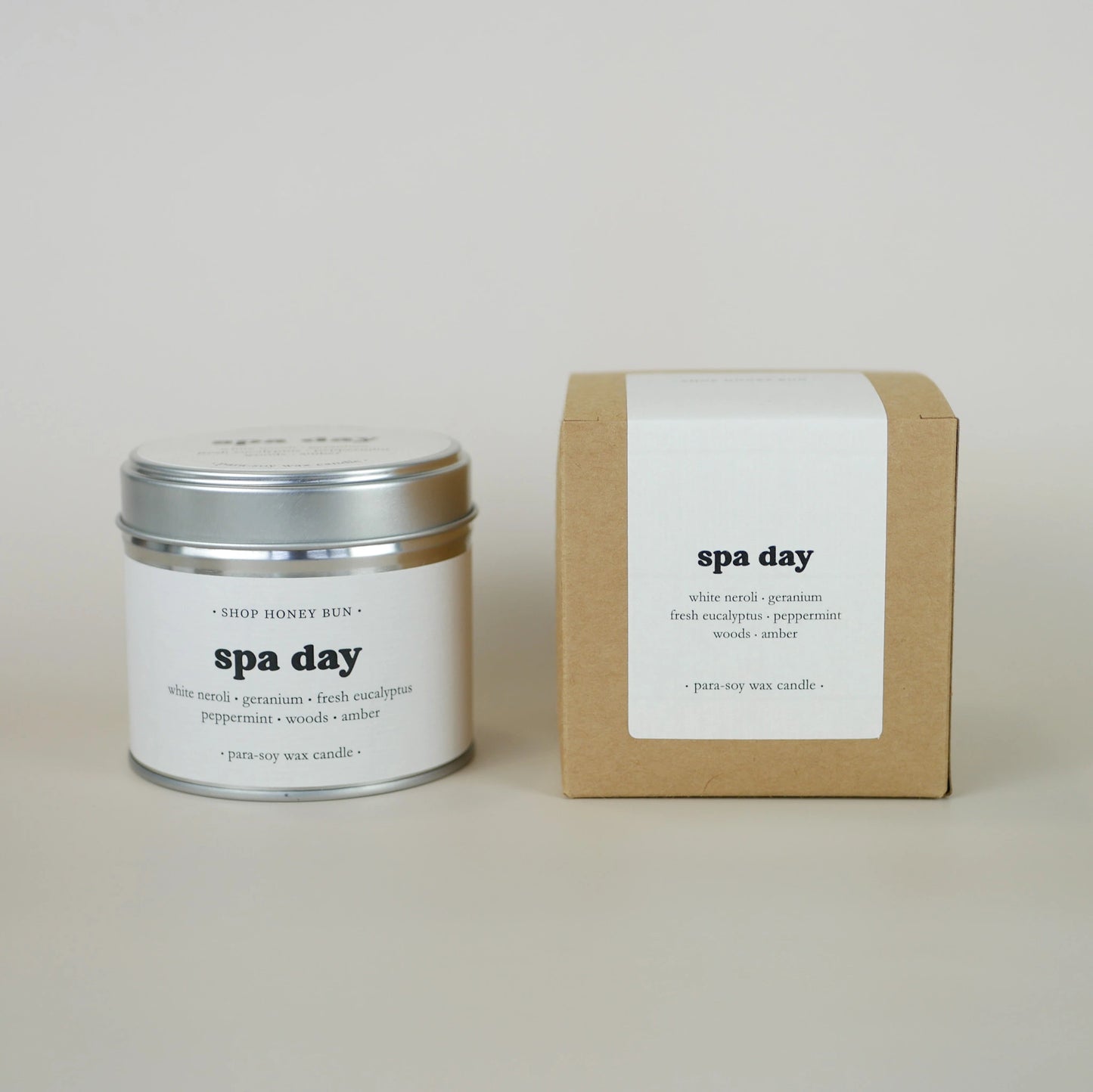A 30 hour burn time spa day scented tin candle next to a brown kraft box with a pale white paper label