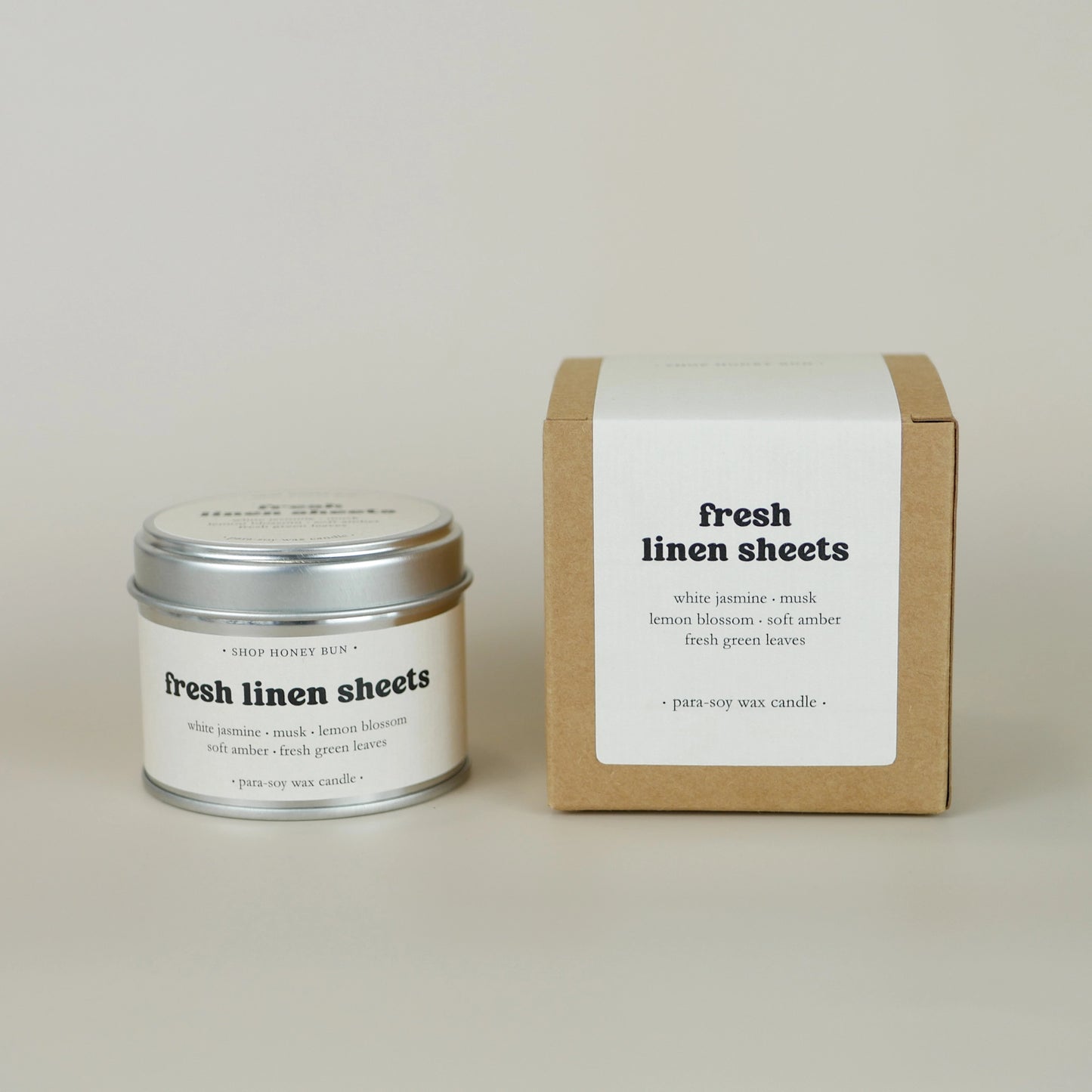 A 20 hour burn time fresh linen sheets scented tin candle next to a brown kraft box with an off-white paper label