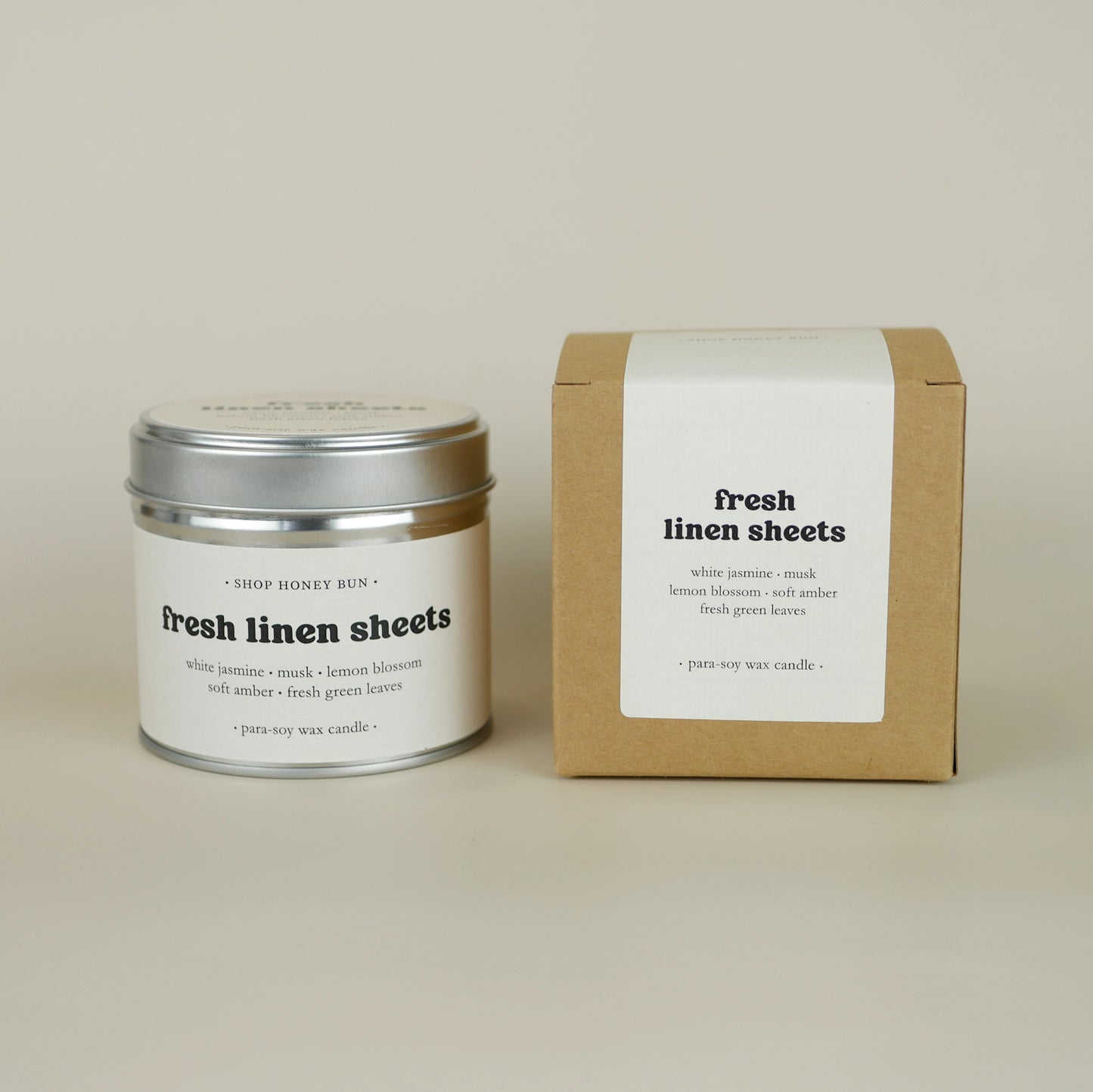 A 30 hour burn time fresh linen sheets scented tin candle next to a brown kraft box with an off-white paper label
