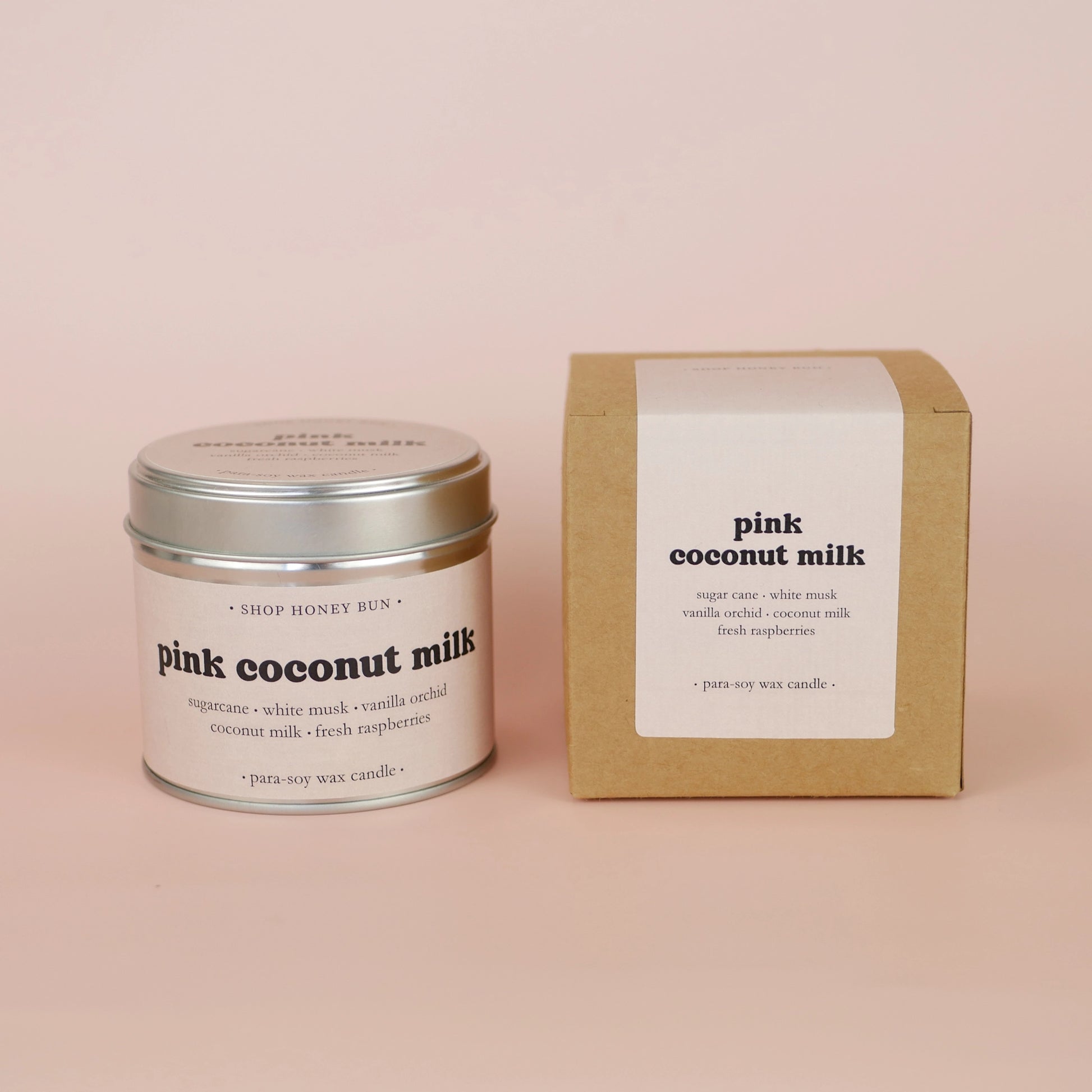 A 30 hour burn time pink coconut milk scented tin candle next to a brown kraft box with a pale pink paper label