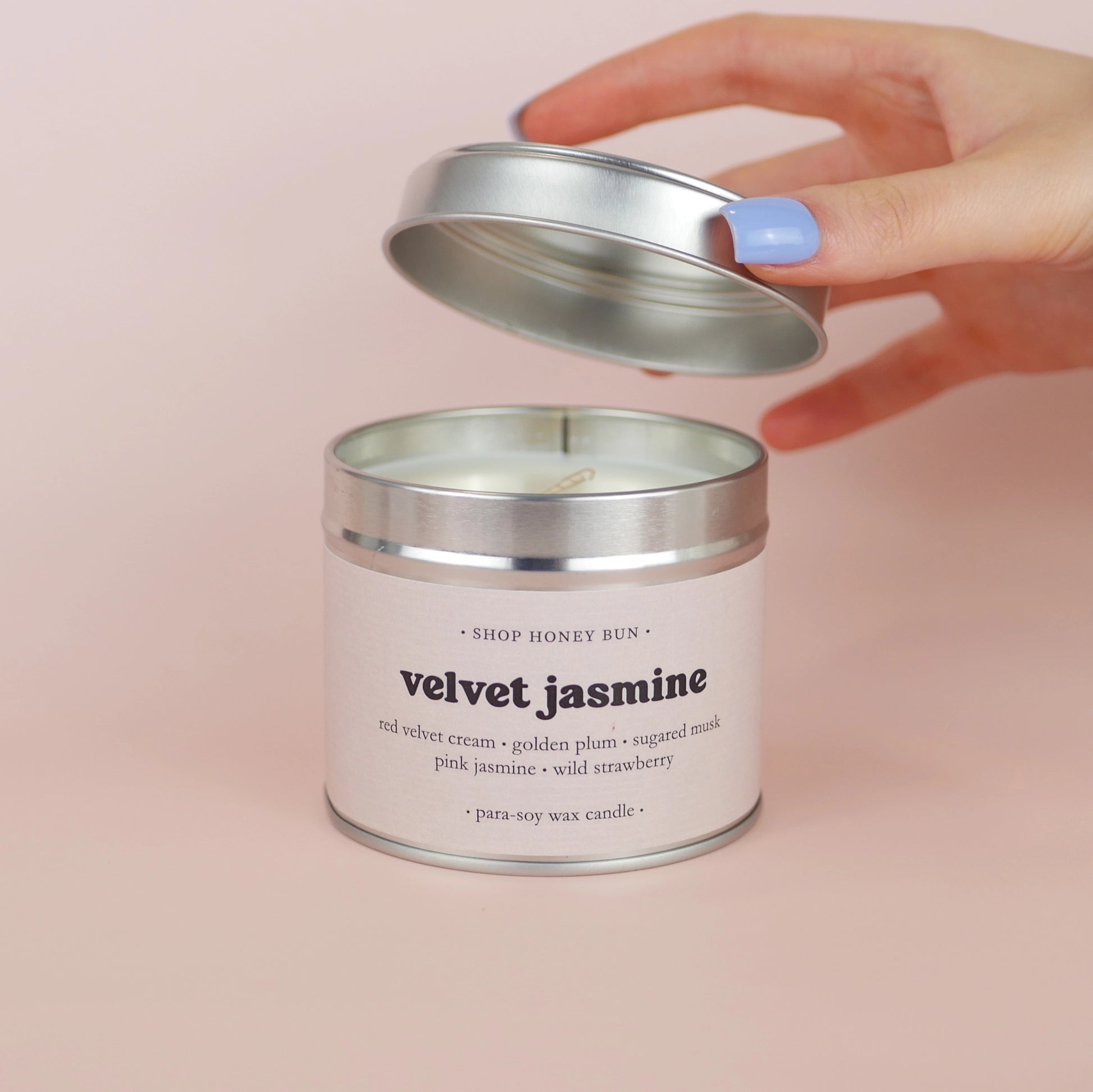 A 30 hour burn time velvet jasmine scented in candle with a hand lifting off the lid to show the candle wick
